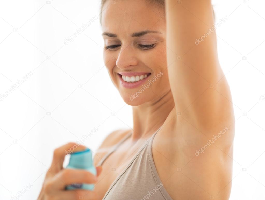 Happy young woman applying deodorant on underarm