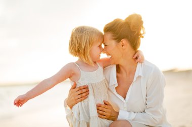 Mutlu anne ve bebek kız sahilde t sarılma portresi