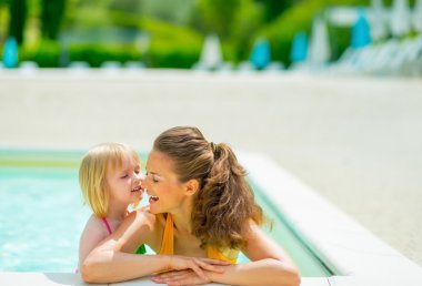 Mutlu anne ve bebek kız yüzme havuzunda portresi