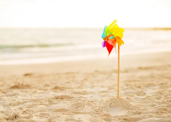 Разноцветная игрушка ветряной мельницы, стоящая на пляже вечером — стоковое фото