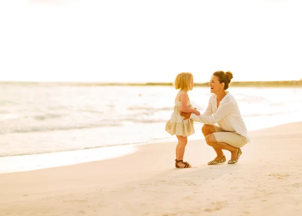 Matka a dítě dívka si hraje na pláži večer — Stock fotografie
