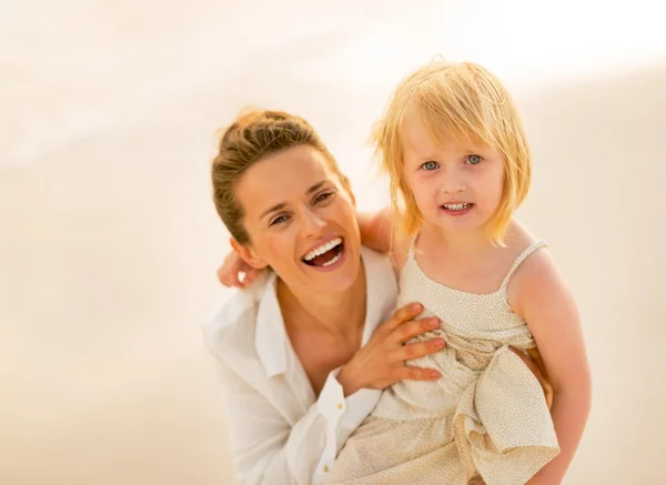 Portrait of smiling mother and baby girl on the beach in the eve — Stock Photo, Image