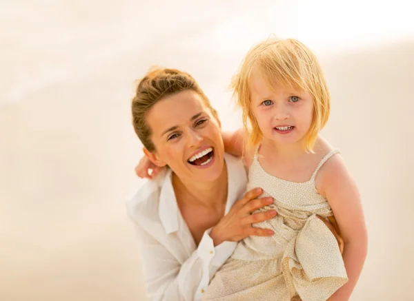 Retrato de la madre sonriente y la niña en la playa en la víspera — Foto de Stock