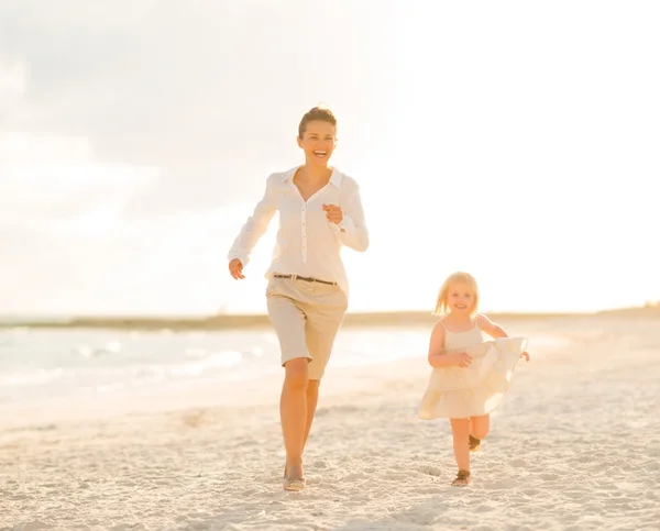 Madre y niña corriendo en la playa por la noche — Foto de Stock