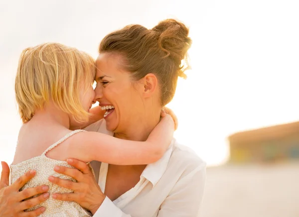 Retrato de la madre sonriente y la niña abrazándose en la playa en — Foto de Stock