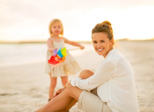 Mor og baby pige bruger tid på stranden om aftenen - Stock-foto