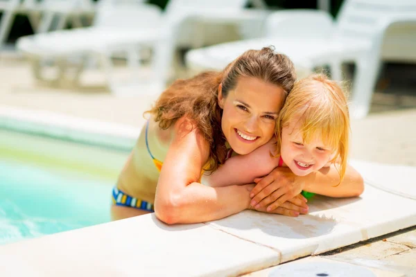 Portræt af smilende mor og baby pige i swimmingpool - Stock-foto