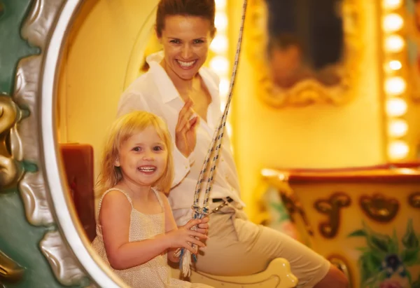 Retrato de madre feliz y niña montado en carrusel — Foto de Stock