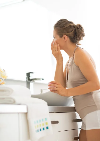 Jeune femme appliquant la crème dans la salle de bain — Photo