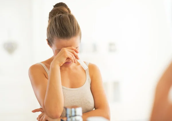 Concerned young woman with pregnancy test in bathroom — Stock Photo, Image