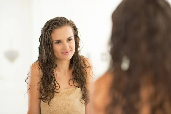 Portrait of young woman with wet hair looking in mirror — Stock Photo, Image