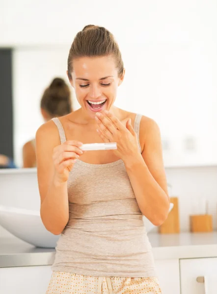 Happy young woman looking on pregnancy test — Stock Photo, Image