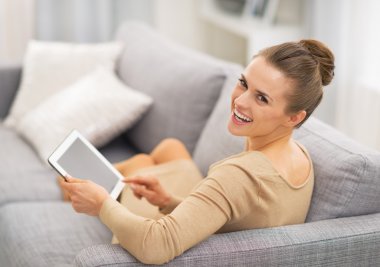 Kanepede oturan ve tablet p kullanarak mutlu genç kadın portresi