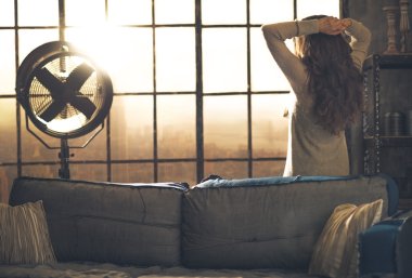 Loft daire penceresinde arayan genç kadın. arka görünüm
