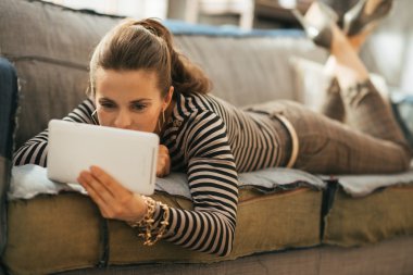 Genç kadın kanepede döşenmesi ve tablet PC'yi kullanma