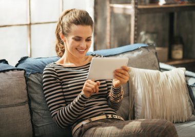 Mutlu genç kadın loft apartmen otururken Tablet PC'yi kullanma