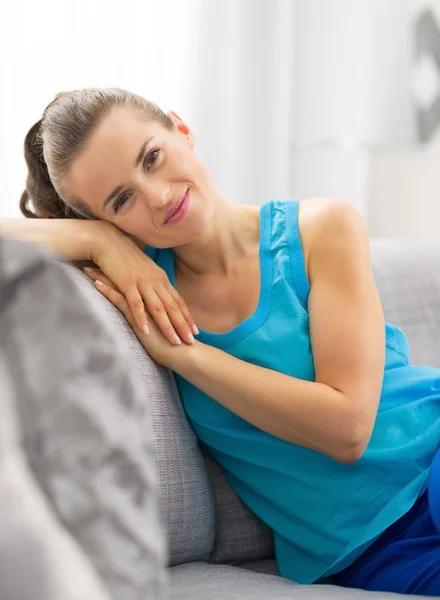 Portret van gelukkige jonge vrouw zitten in woonkamer — Stockfoto