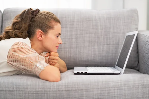 Junge Frau liegt auf Couch und benutzt Laptop — Stockfoto