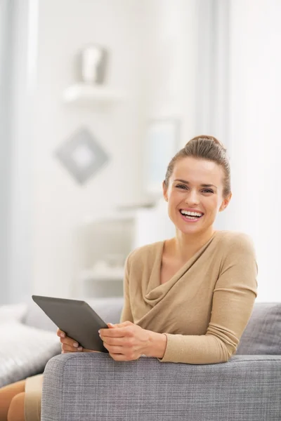 Portret van gelukkige jonge vrouw met tablet pc in woonkamer — Stockfoto