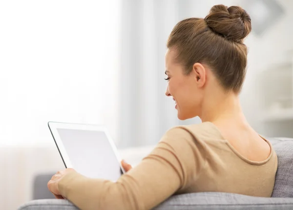 Jonge vrouw zittend op de Bank en de tablet pc gebruiken. Achteraanzicht — Stockfoto