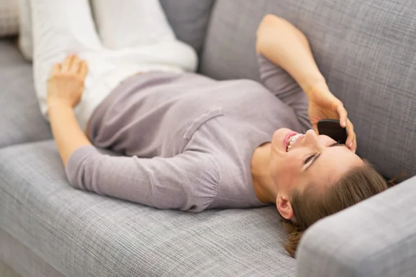 Heureuse jeune femme allongée sur le canapé et parlant téléphone portable — Photo