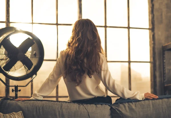 Mujer joven mirando por la ventana en el apartamento loft. visión trasera — Foto de Stock