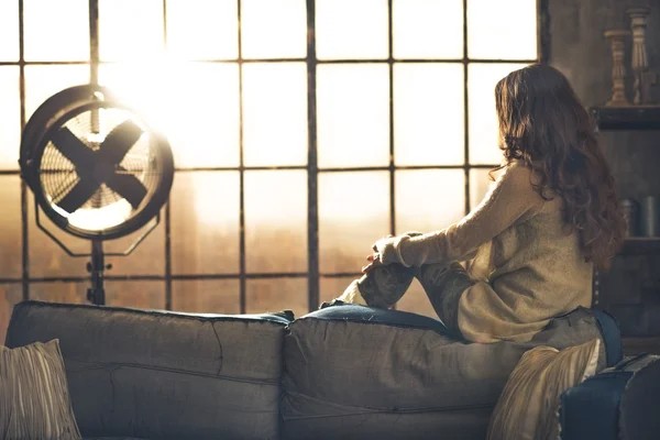 Jovem mulher olhando na janela no apartamento loft. vista traseira — Fotografia de Stock