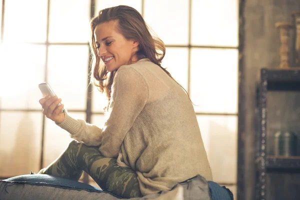 Young woman writing sms in loft apartment — Stock Photo, Image