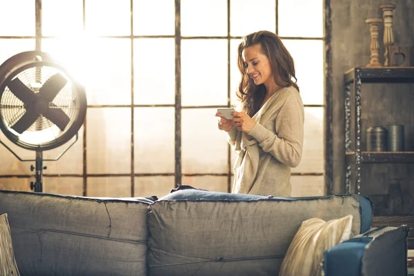 Jeune femme écrivant sms dans appartement loft — Photo