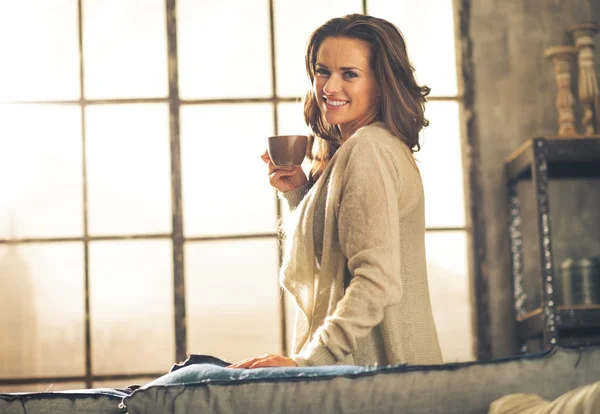 Gelukkig jonge vrouw genieten van kopje koffie in Zolder Appartement — Stockfoto