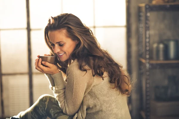 Portret van ontspannen jonge vrouw met kop koffie in loft uit elkaar — Stockfoto