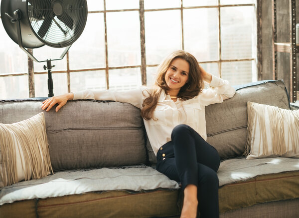 Relaxed young woman sitting on couch in loft apartment