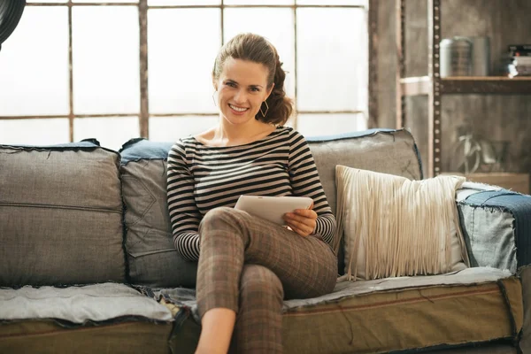 Happy young woman with tablet pc sitting in loft apartment — Stock Photo, Image