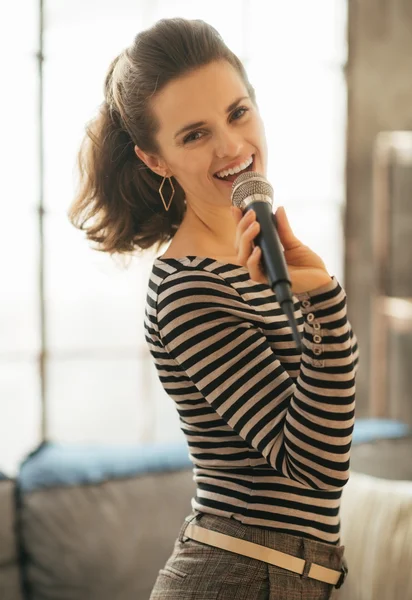 Πορτρέτο του χαμογελώντας νεαρή γυναίκα που τραγουδούν με το μικρόφωνο στο πατάρι — Φωτογραφία Αρχείου
