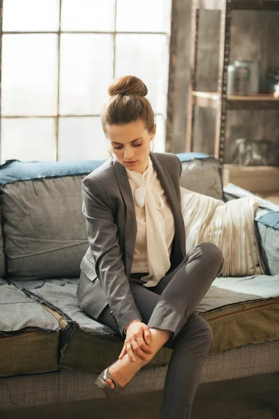 Mulher de negócios atenciosa no apartamento loft verificando pernas cansadas — Fotografia de Stock