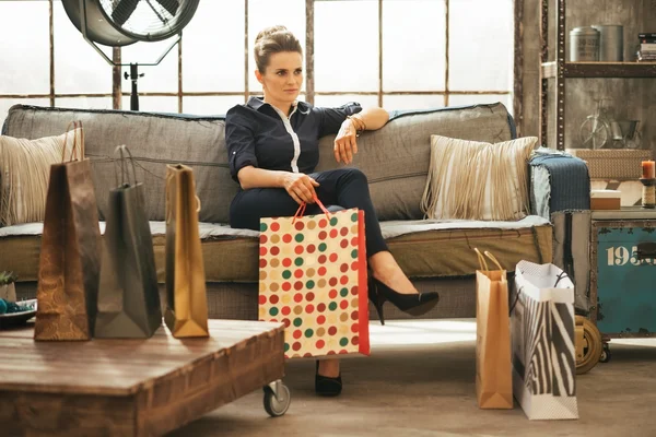 Розслаблена молода жінка з сумками, що сидять в квартирі на горищі — стокове фото