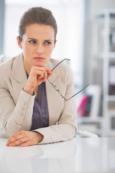 Thoughtful business woman with eyeglasses in office — Stock Photo, Image