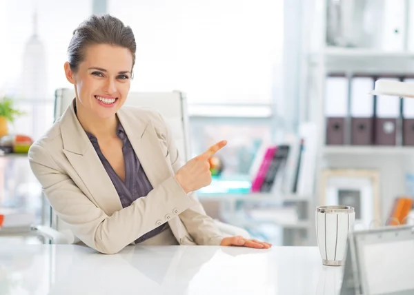 Zufriedene Geschäftsfrau im Büro zeigt auf Kopierraum — Stockfoto