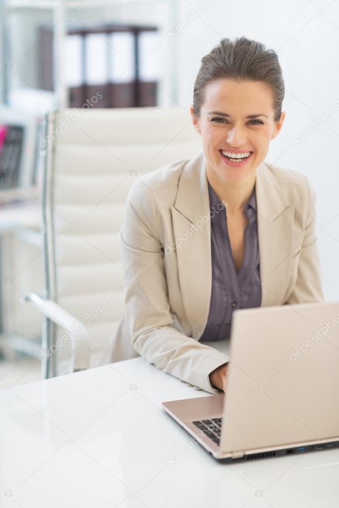 Happy business woman working on laptop in office