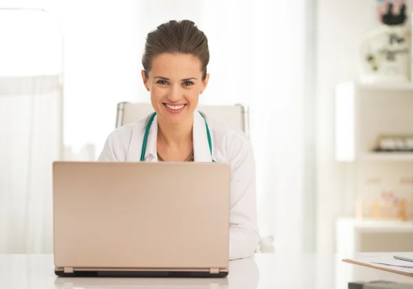 Happy médecin femme travaillant sur ordinateur portable dans le bureau — Photo