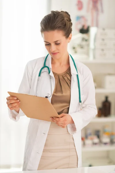 Mujer doctora mirando en portapapeles —  Fotos de Stock