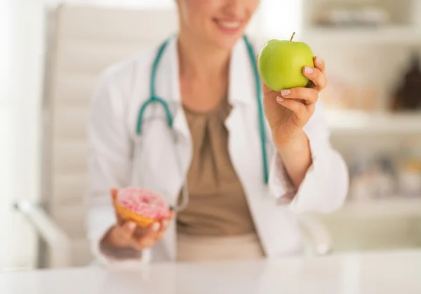 Nahaufnahme einer Ärztin, die sich zwischen Apfel und Donut entscheidet — Stockfoto