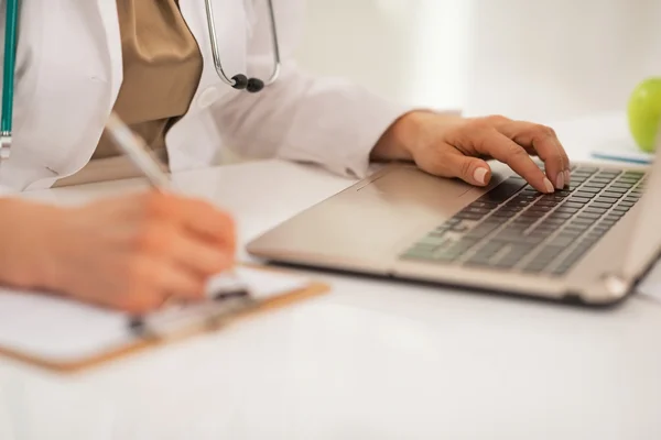 Close-up na mulher médica trabalhando no laptop no escritório — Fotografia de Stock