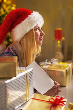 Teenager girl in santa hat with christmas postcard among christm clipart