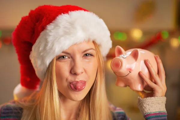 Portrait of teenager girl in santa hat showing tongue and piggy — Stock Photo, Image