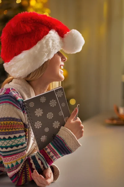 微笑的十几岁的女孩在圣诞老人的帽子，拿着记事本的肖像 — 图库照片
