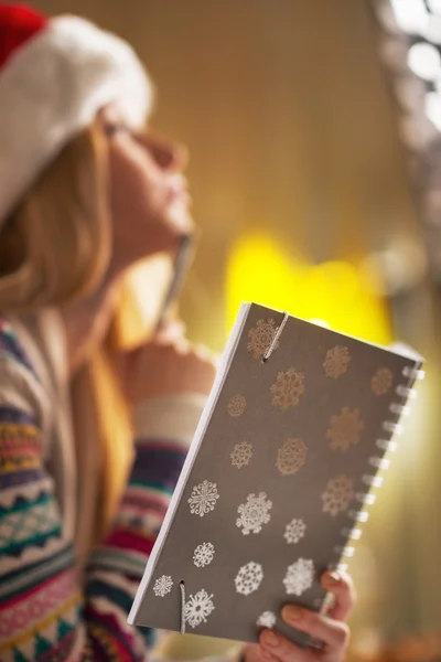 Close-up op doordachte tiener meisje in Kerstman hoed bedrijf Kladblok — Stockfoto
