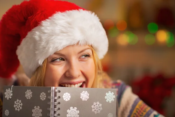 Portrait d'adolescente souriante en chapeau de Père Noël se cachant derrière pas — Photo