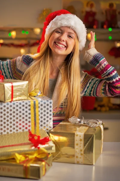 Glückliches Teenager-Mädchen mit Weihnachtsmütze und einem Stapel Weihnachtsgeschenke — Stockfoto