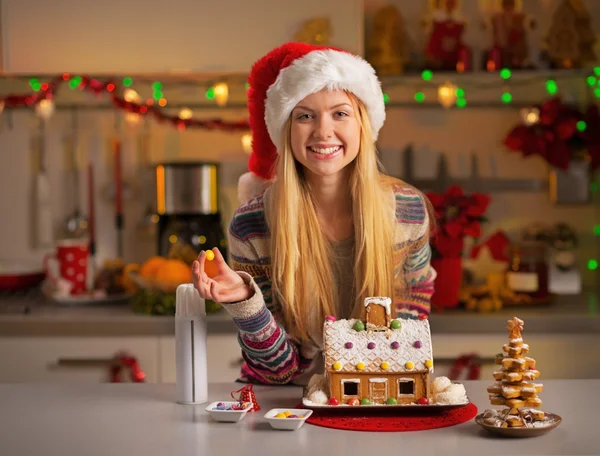 Portrait of smiling teenager girl in santa hat decorating christ — Stock Photo, Image